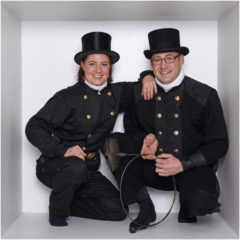 Eine Frau und ein Mann in Schornsteinfeger-Kleidung